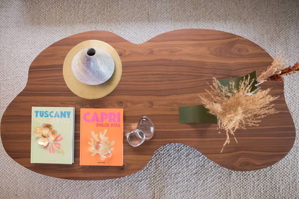 Sala de estar com paleta bege e mesa de centro de madeira com formato orgânico.