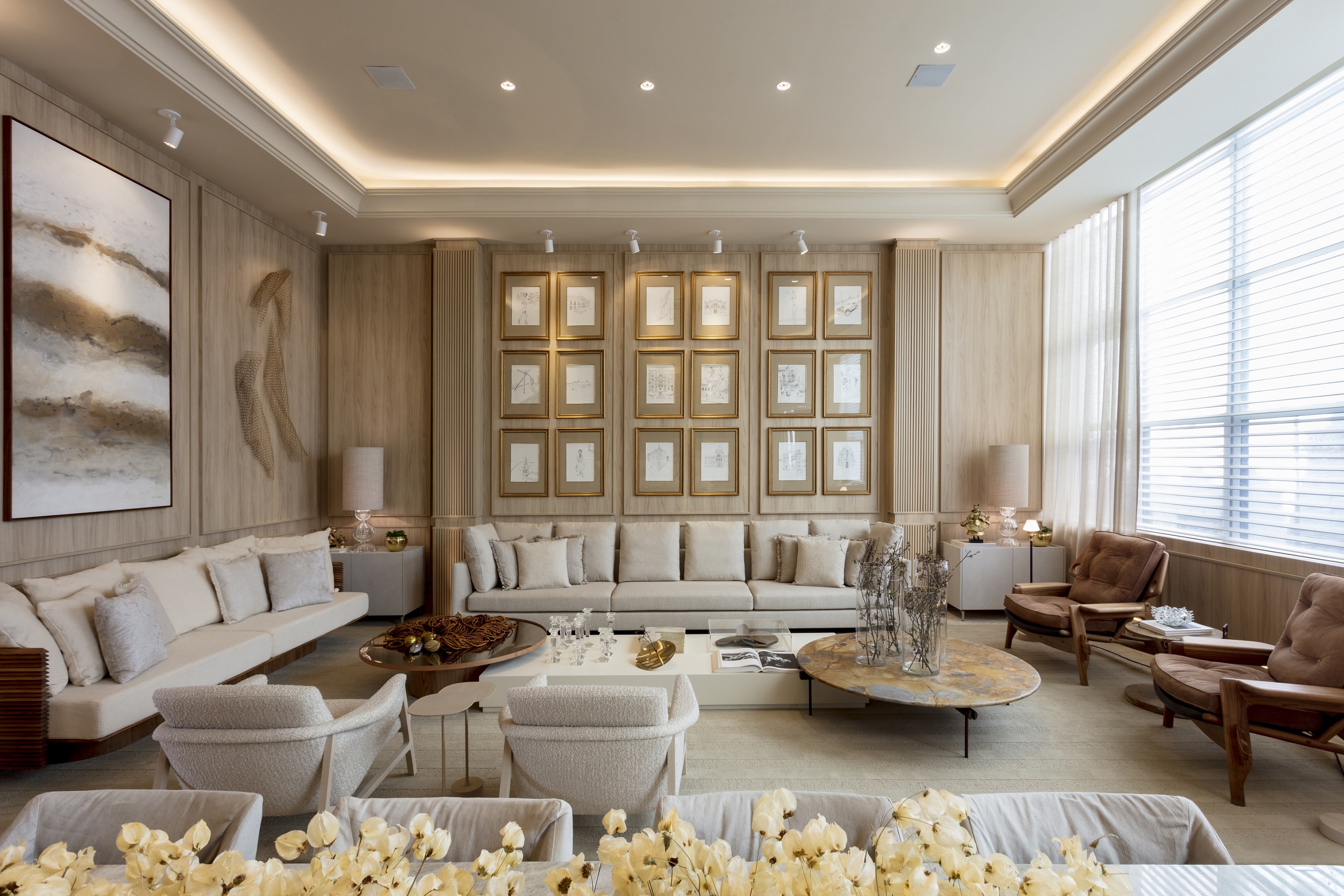 Sala de estar com paleta bege, móveis planejados e parede revestida de madeira com boiseries.