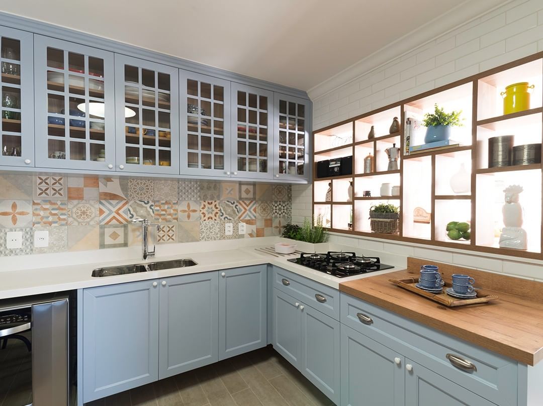 Projetos de Carina dal Fabbro. Cozinha com armários azuis e backsplash de azulejos coloridos.