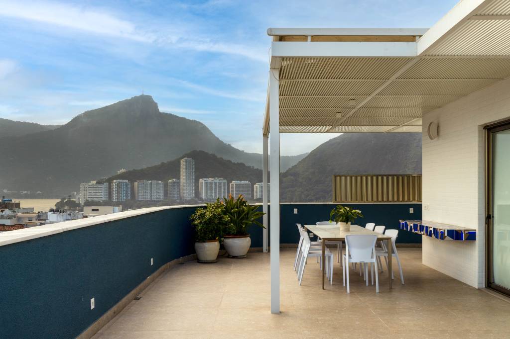 Reforma adapta duplex com vista para o Cristo para família de três adultos. Projeto de Andrea Chicaro. Na foto, varanda gourmet com vista para o Cristo, mesa e plantas.