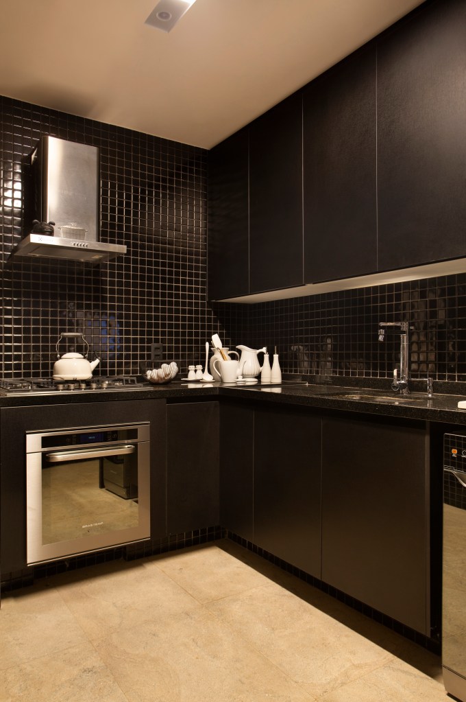 Projeto de Ricardo Melo e Rodrigo Passos. Na foto, cozinha com marcenaria e revestimentos pretos.