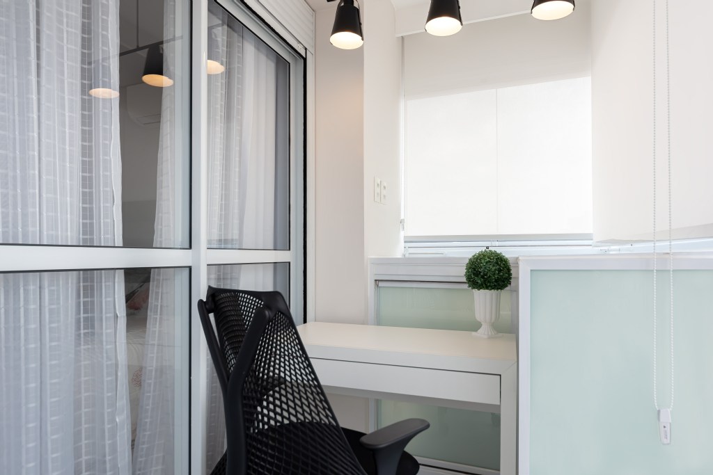 Projeto de Palladino Arquitetura. Na foto, home office pequeno em varanda com bancada branca.