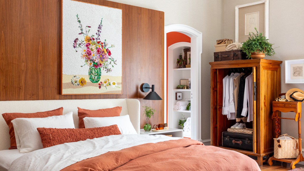 Suíte ganha conforto quarto de hotel com paredes de madeira. Projeto de Paula Muller para a CASACOR Rio 2023. Na foto, quarto com parede de madeira, e armário.
