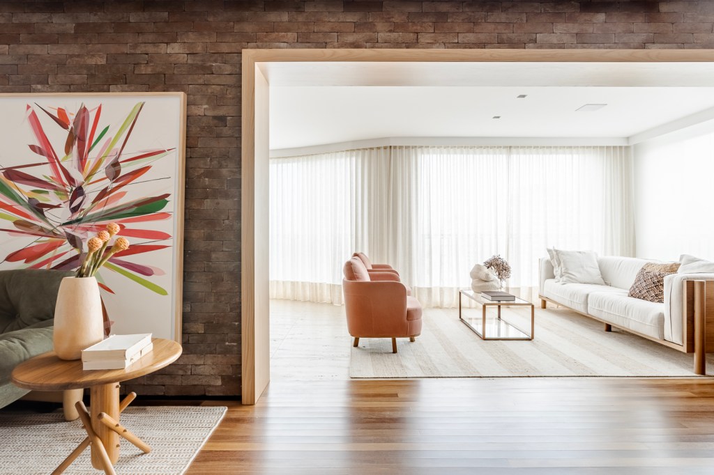 Tijolinhos revestem todas as paredes do living deste apê de 310 m². Projeto de Très Arquitetura. Na foto, sala de estar com parede de tijolinhos e quadro.