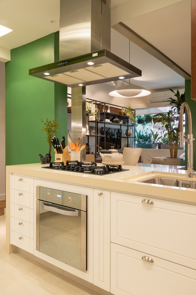 Apê pequeno de 71 m² ganha décor feminino, colorido e repleto de plantas Projeto de Marcela Martins. Na foto, cozinha com ilha e armários verdes.