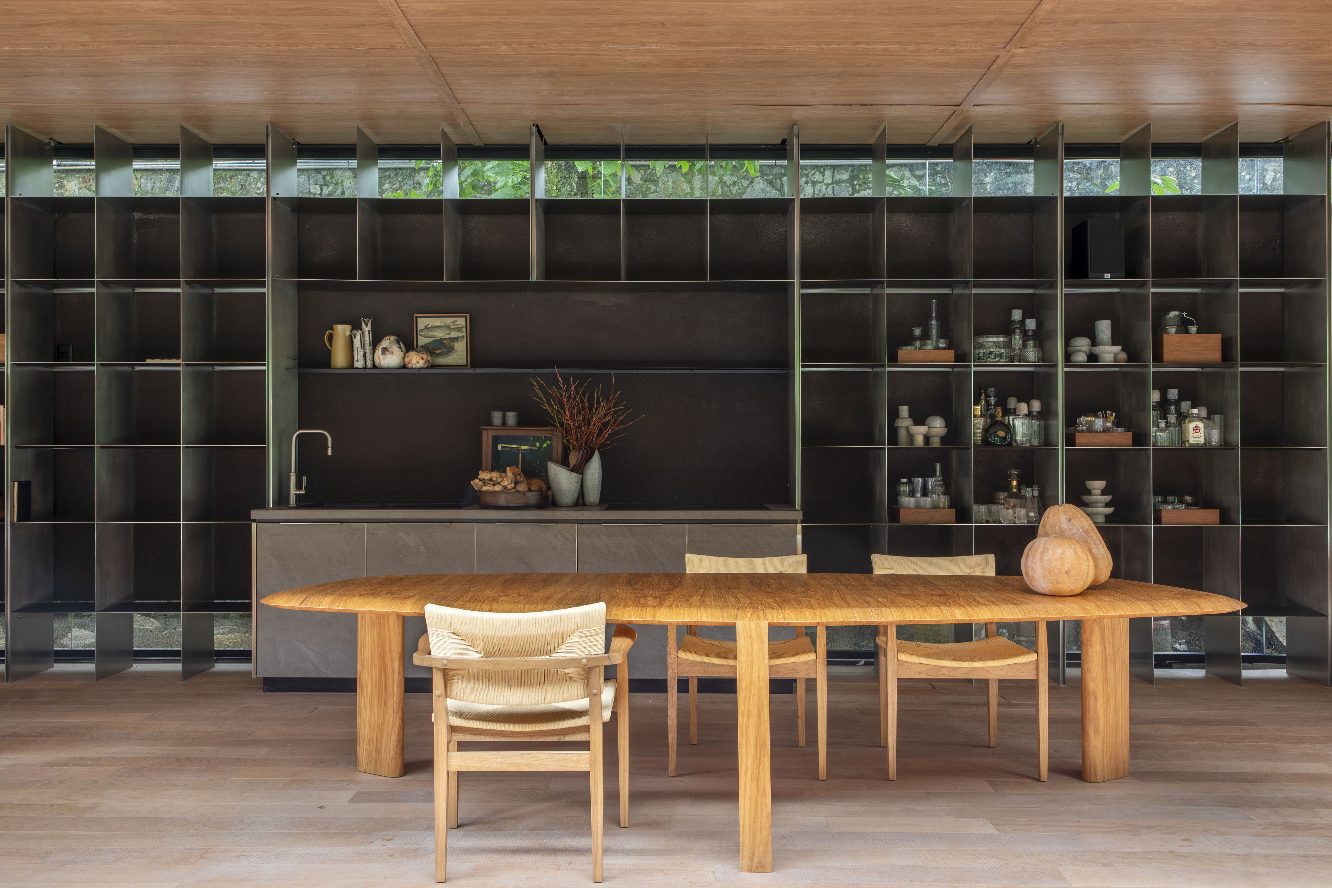 Pavilhão Deca - ambiente de João Panaggio para a CASACOR Rio 2023. Na foto, cozinha com mesa e cadeiras de madeira.