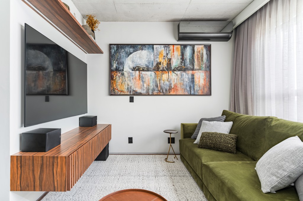 Apê de 140 m² com estilo industrial tem pia no quarto e jardim de cactos. Projeto de Gabriela Prado. Na foto, sala de TV com sgfá verde e quadro.