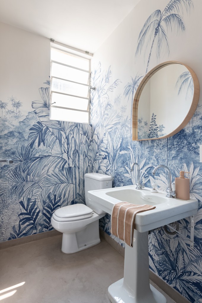 Apê de 200 m² ganha décor que mescla móveis de acervo e peças novas. Projeto do Estúdio Maré. Na foto, lavabo com papel de parede de plantas azuis.