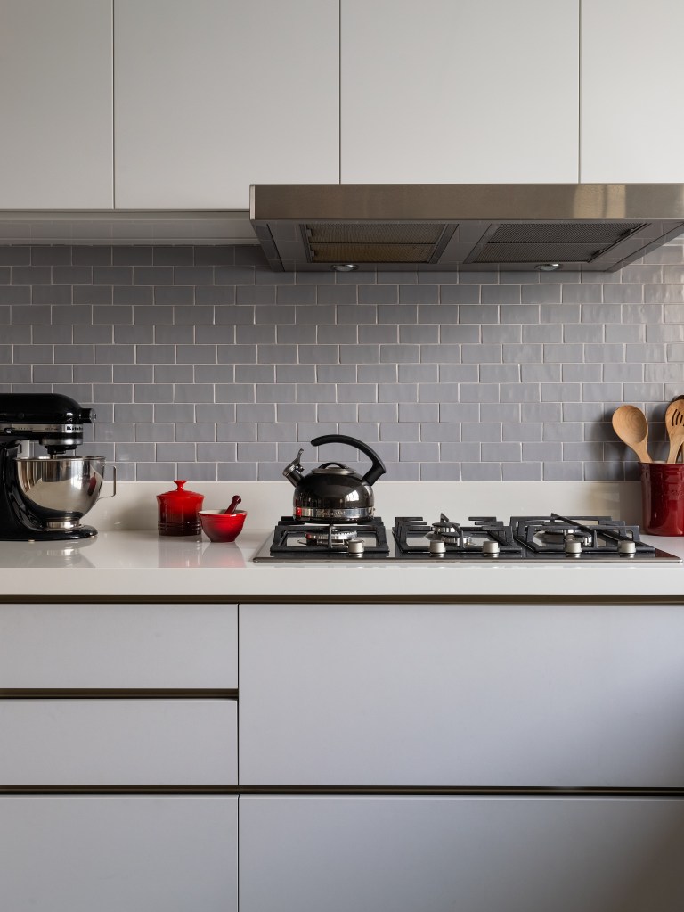 Projeto de Fernanda Dabbur. Na foto, cozinha com marcenaria cinza, bancada cinza clara e backsplash de tijolinhos cinzas.