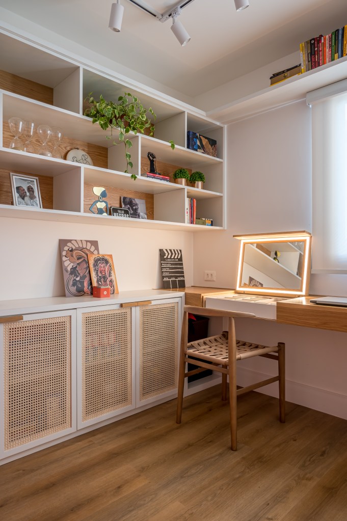 Projeto de Paula Scholte. Na foto, home office com estante de marcenaria com nichos, bancada de madeira e penteadeira retrátil.