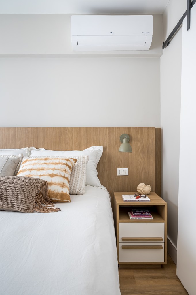 Projeto de Paula Scholte. Na foto, quarto com cama de casal, cabeceira de madeira e mesinha lateral.