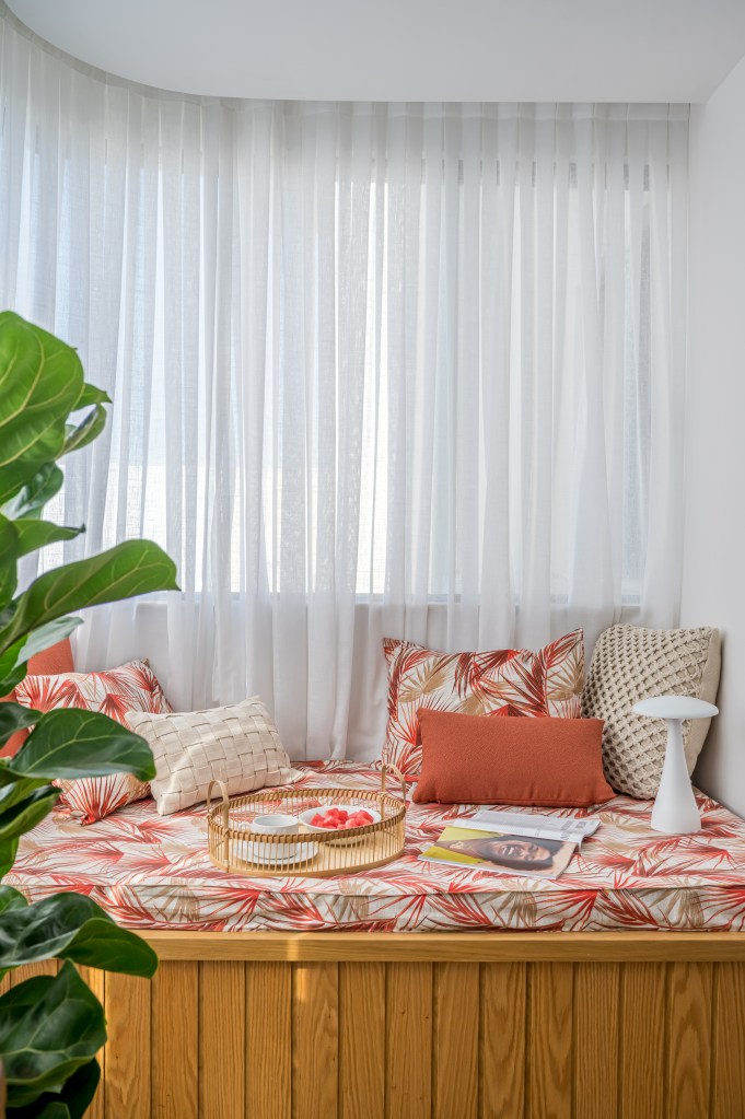 Dicas fáceis para montar um cantinho da leitura em casa. Projeto de Paula Scholte. Na foto, varanda integrada com futon, cortina branca, plantas.