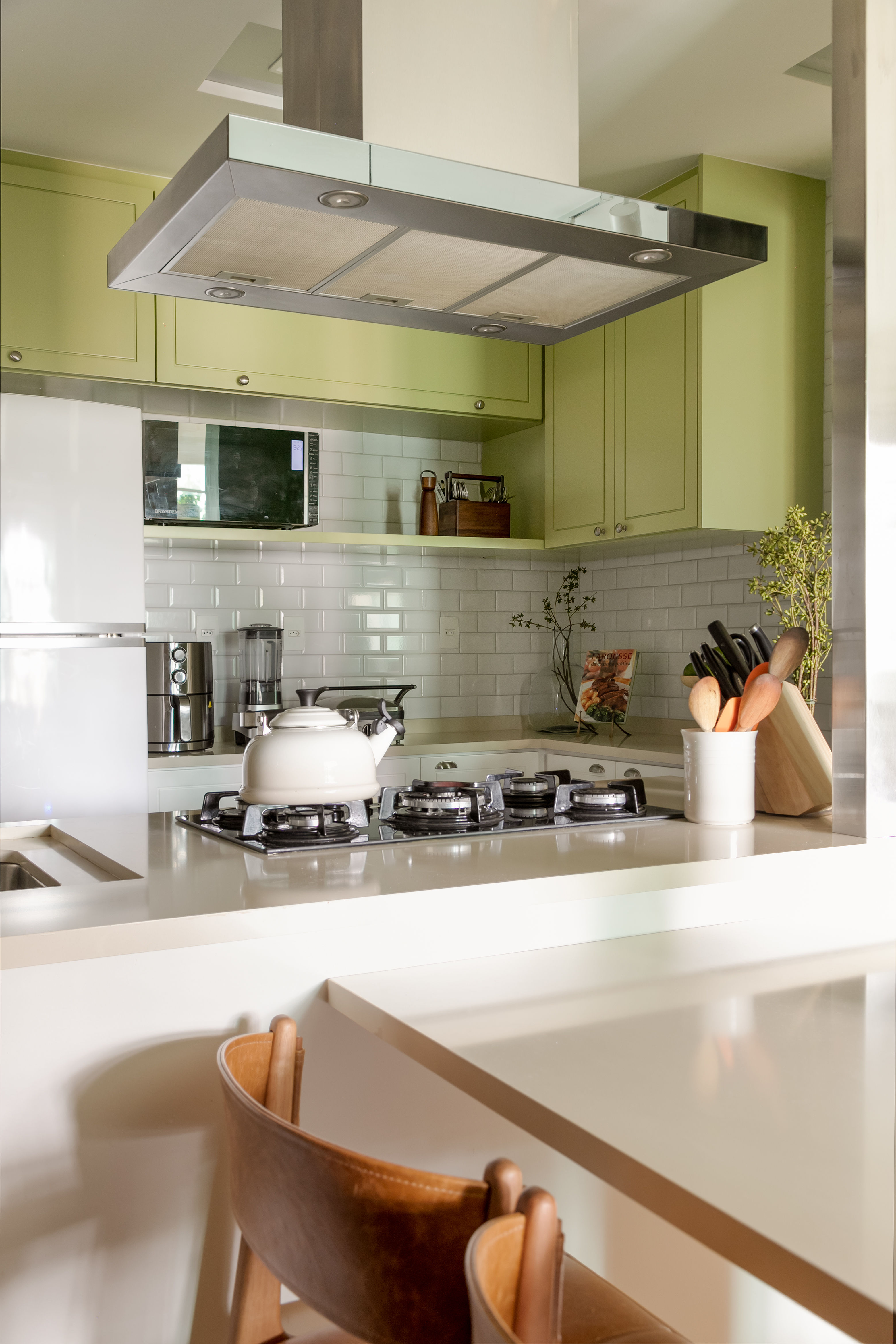 Projeto de Marcela Martins. Na foto, cozinha integrada com bancada branca e marcenaria verde.