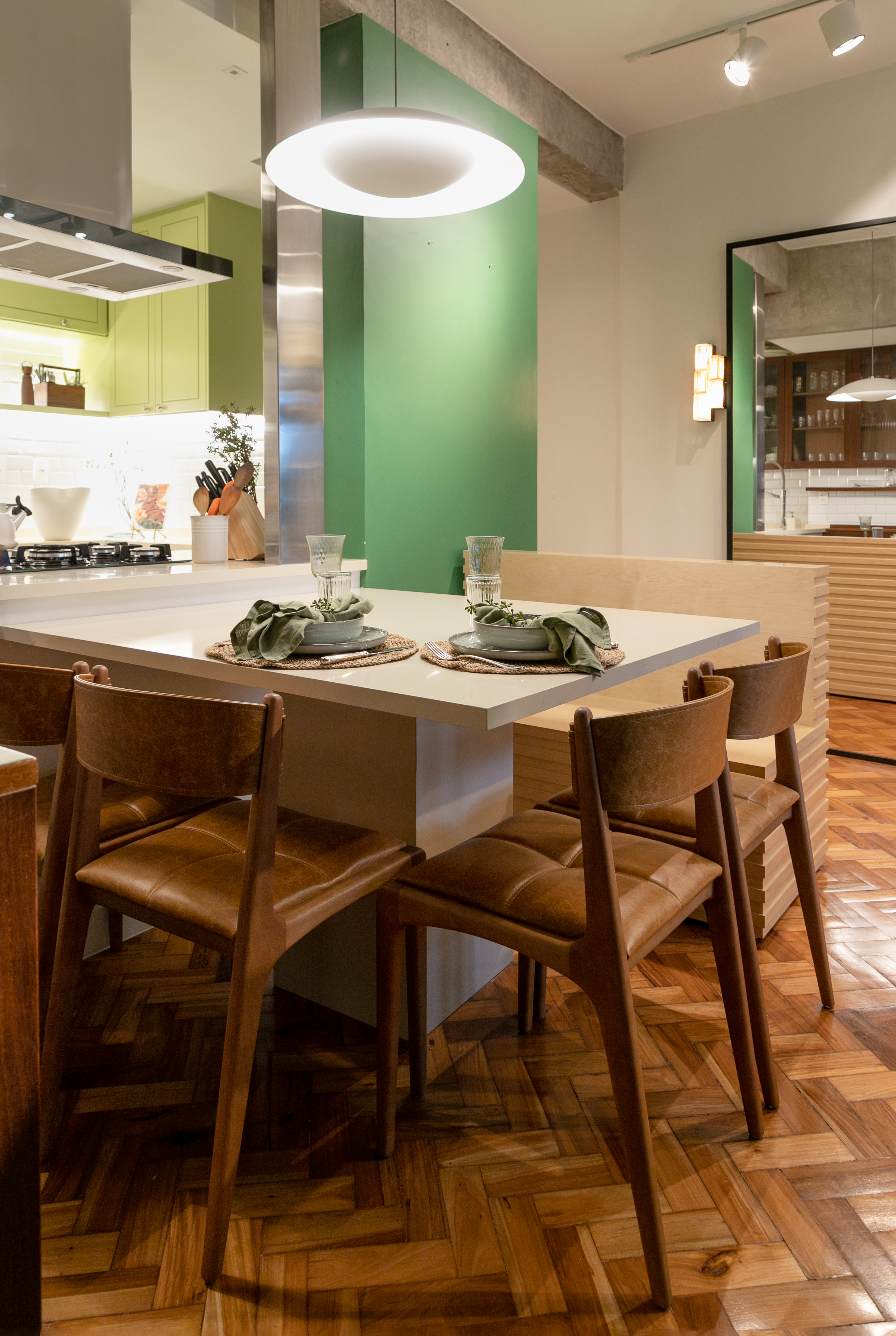 Projeto de Marcela Martins. Na foto, cozinha integrada com sala de jantar, parede verde e mesa de jantar branca.