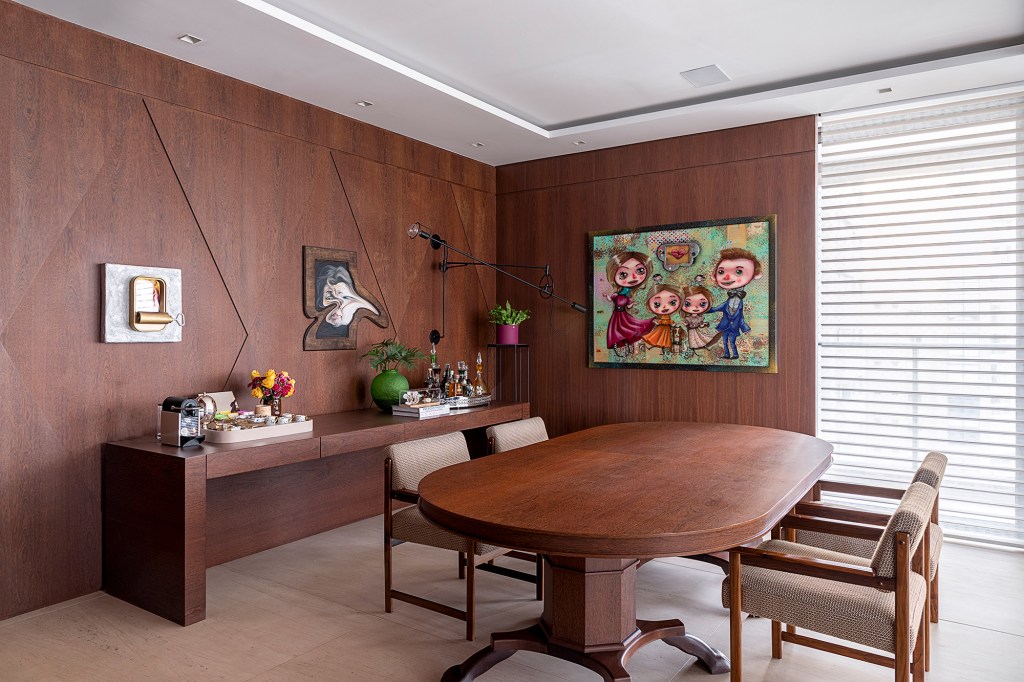 Apê descolado de 632 m² tem sofás coloridos e adega para mil garrafas. Projeto de Ana Weege. Na foto, sala de jantar com parede de madeira e obras de arte nas paredes,