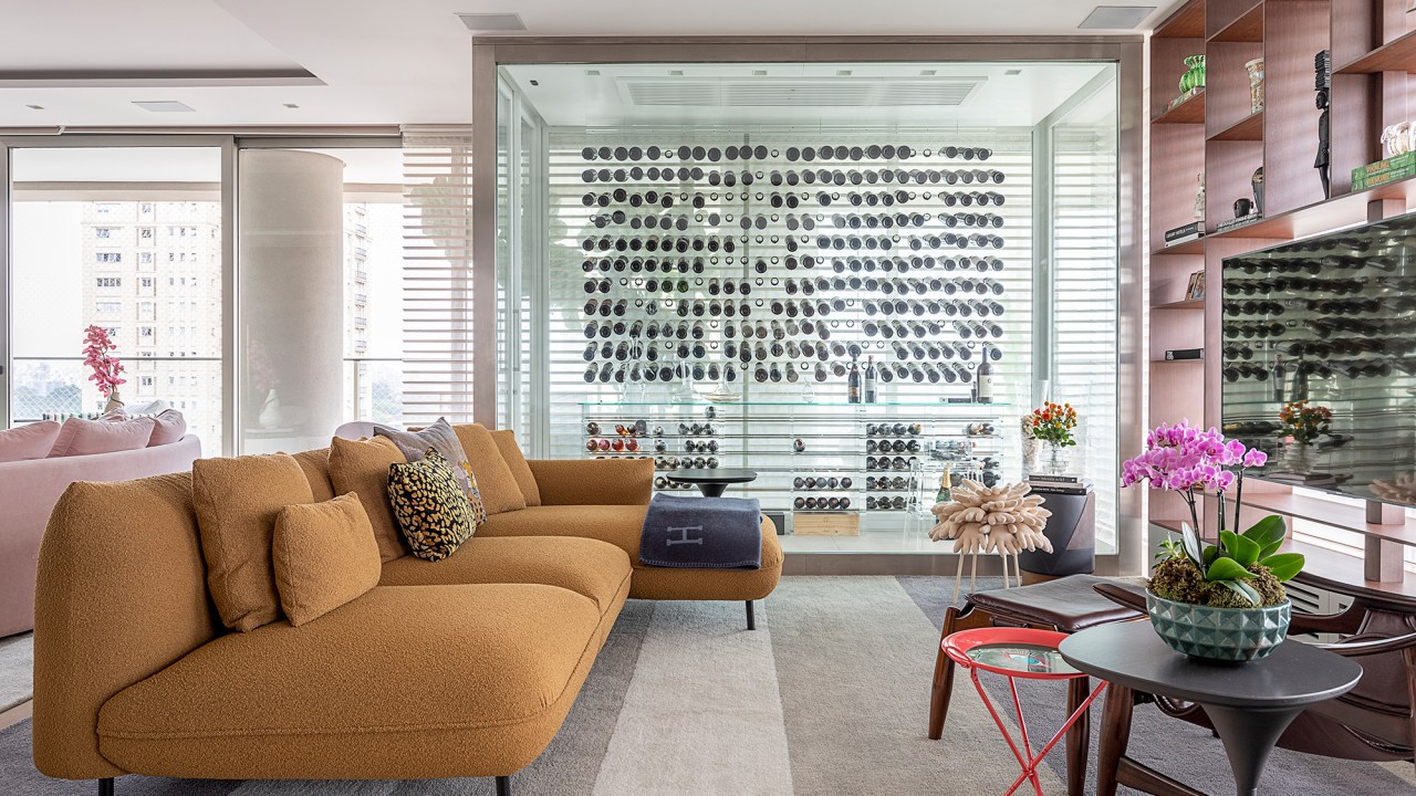 Apê descolado de 632 m² tem sofás coloridos e adega para mil garrafas. Projeto de Ana Weege. Na foto, sala de TV com adega e estante vazada.