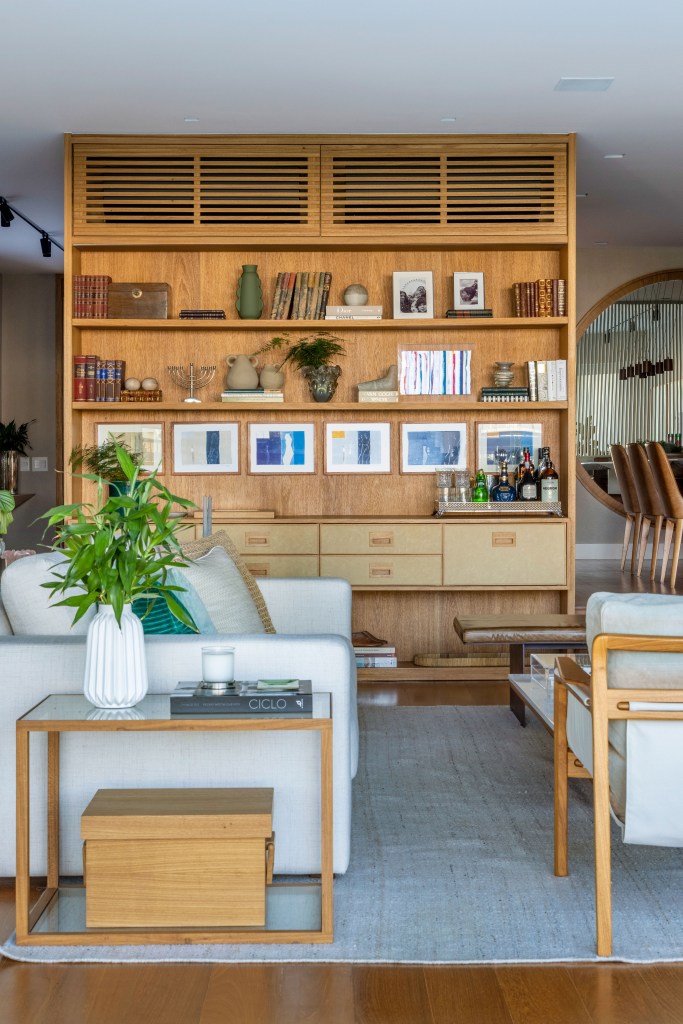 casa-5-andares-ambientes-integrados-piscina-de-borda-infinita-escala-arquitetura-24 Projeto de Escala Arquitetura. Na foto, sala com estante, sofá branco e tapete cinza.