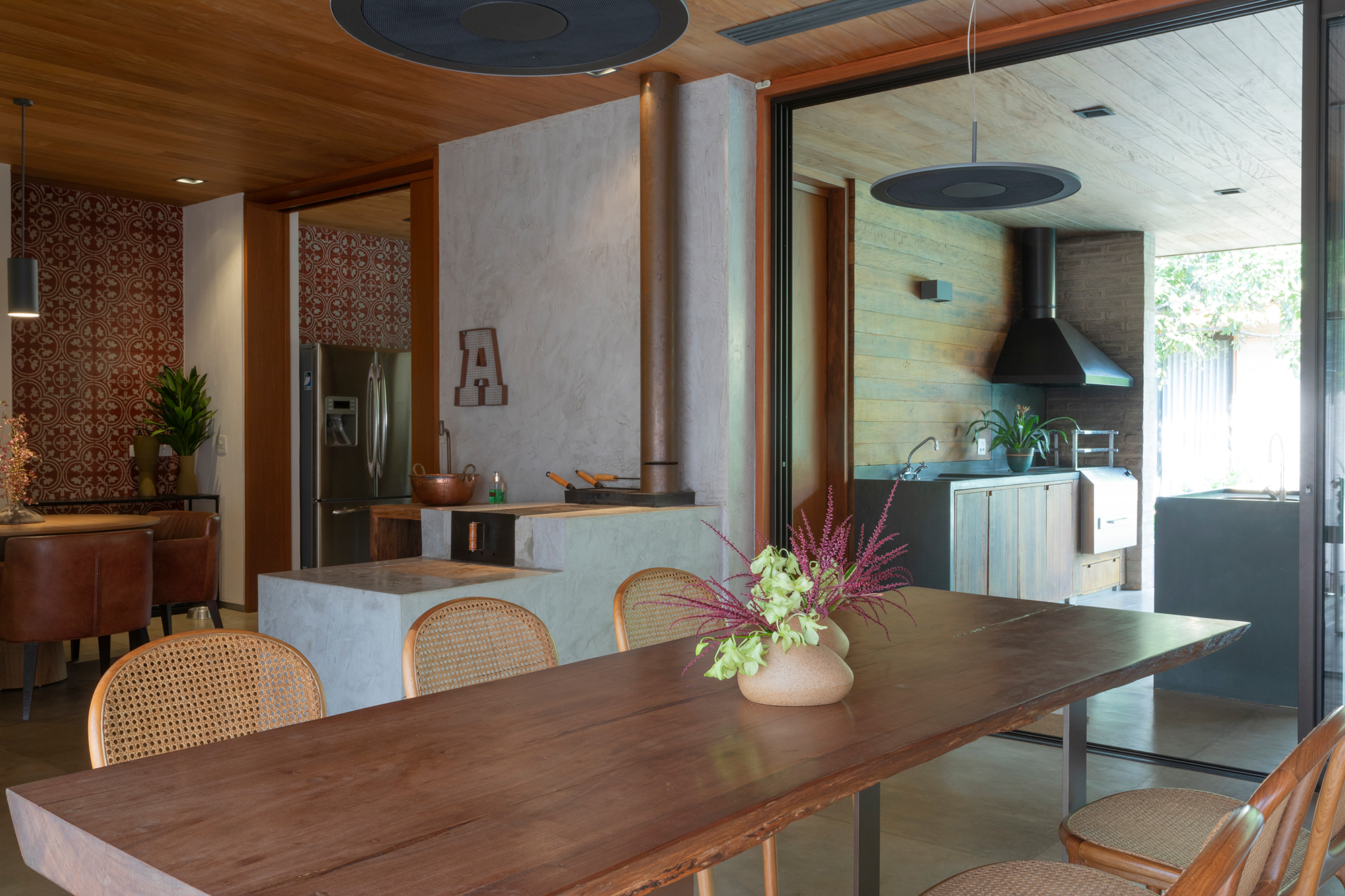 Casa de campo de 818 m² é um verdadeiro refúgio em meio à natureza. Projeto de Daniel Fromer. Na foto, cozinha e sala de jantar com fogao a lenha e mesa de madeira.