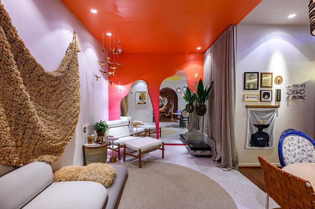 Casa de praia de 55 m² tem décor afetivo e mobiliário 100% brasileiro, Projeto de Hudson Castro para a CASACOR Brasília 2023. NA foto, sala com espelho orgânico e paredes laranjas.