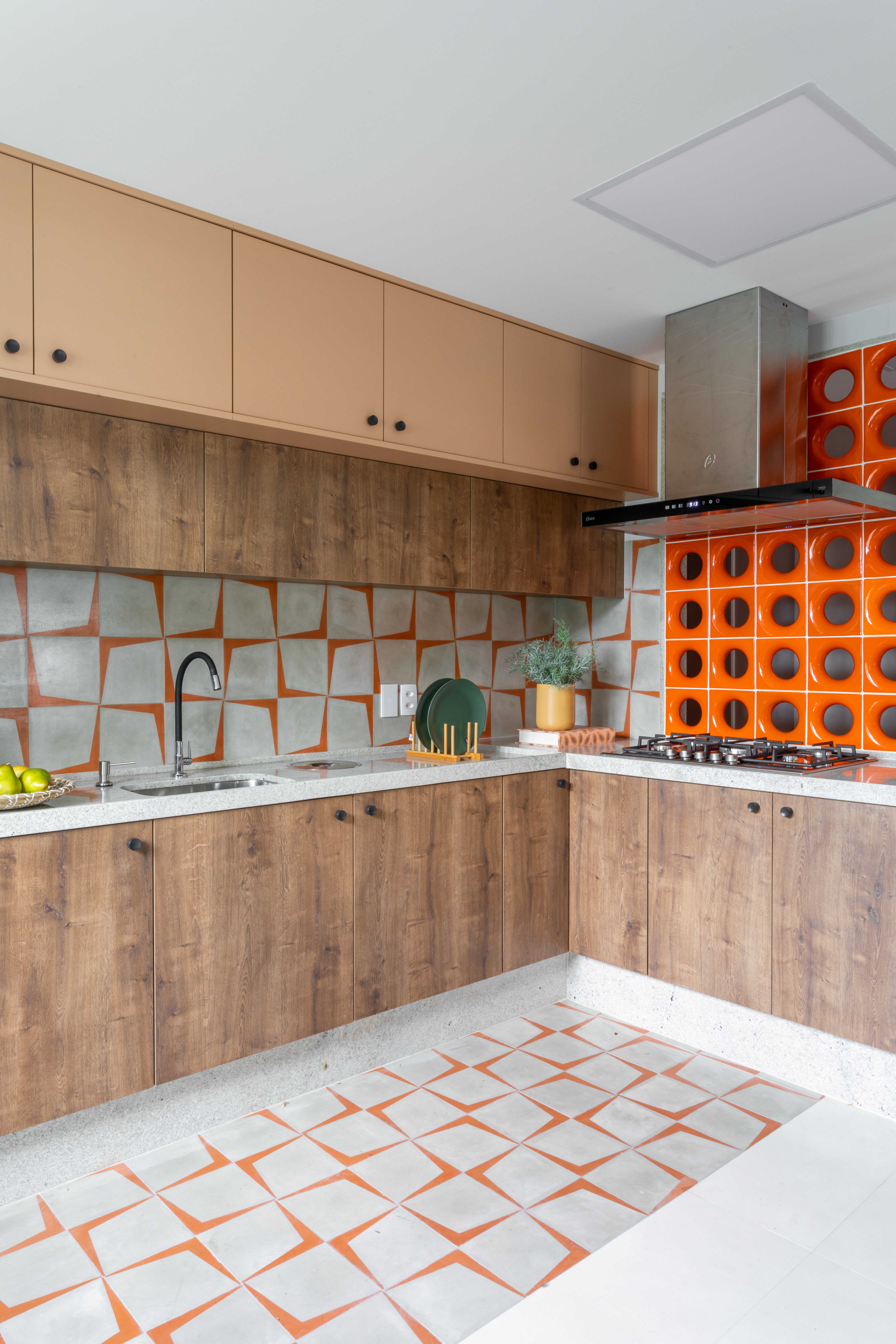 Projeto de Lívia Ornellas. Na foto, cozinha com cobogós laranjas, ladrilhos laranjas, marcenaria e bancada branca.