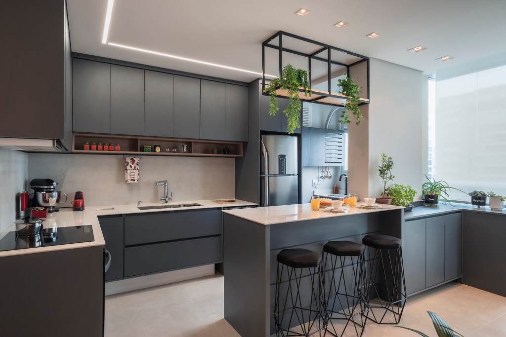 Projeto de PB Arquitetura. Na foto, cozinha integrada com marcenaria preta.