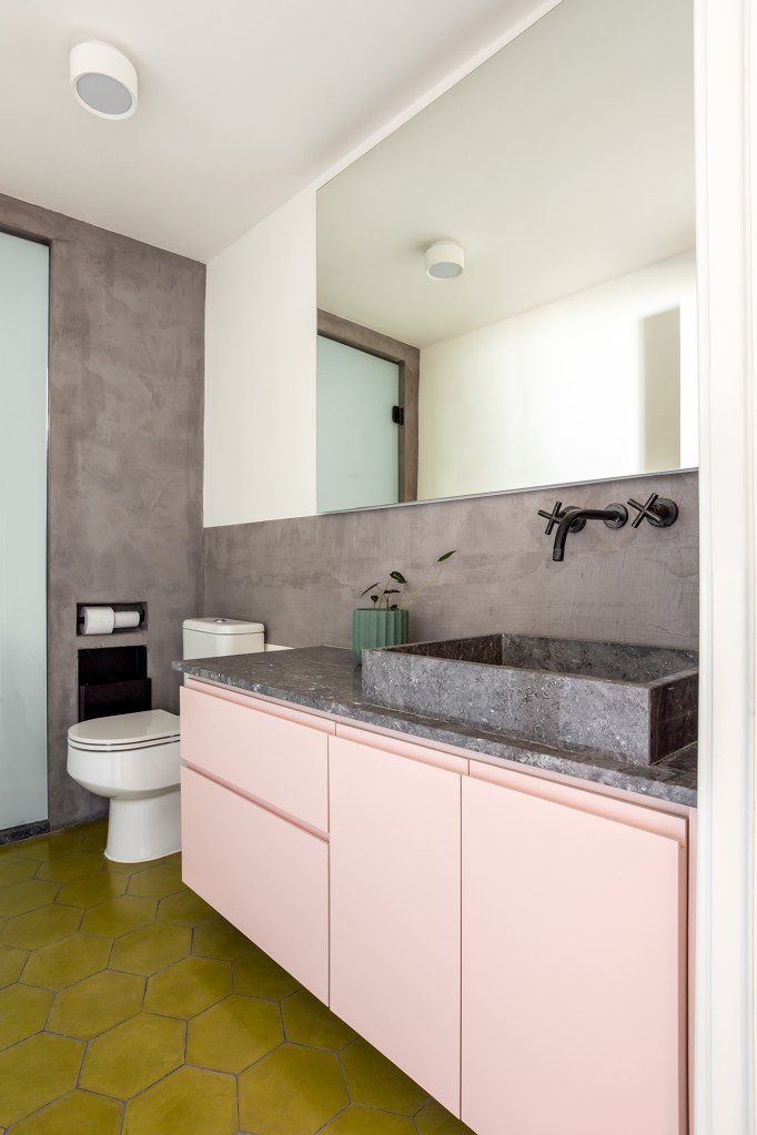 Concreto, verde e rosa marcam o décor deste apê de 110 m². Projeto de MNBR Arquitetos. Na foto, banheiro com marcenaria rosa e tampo de pedra.