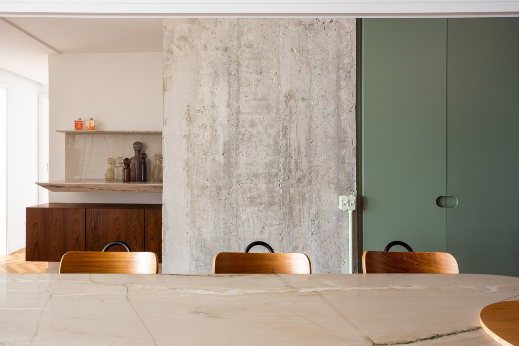Concreto, verde e rosa marcam o décor deste apê de 110 m². Projeto de MNBR Arquitetos. Na foto, mesa de jantar com pilar de concreto, bar e marcenaria verde.