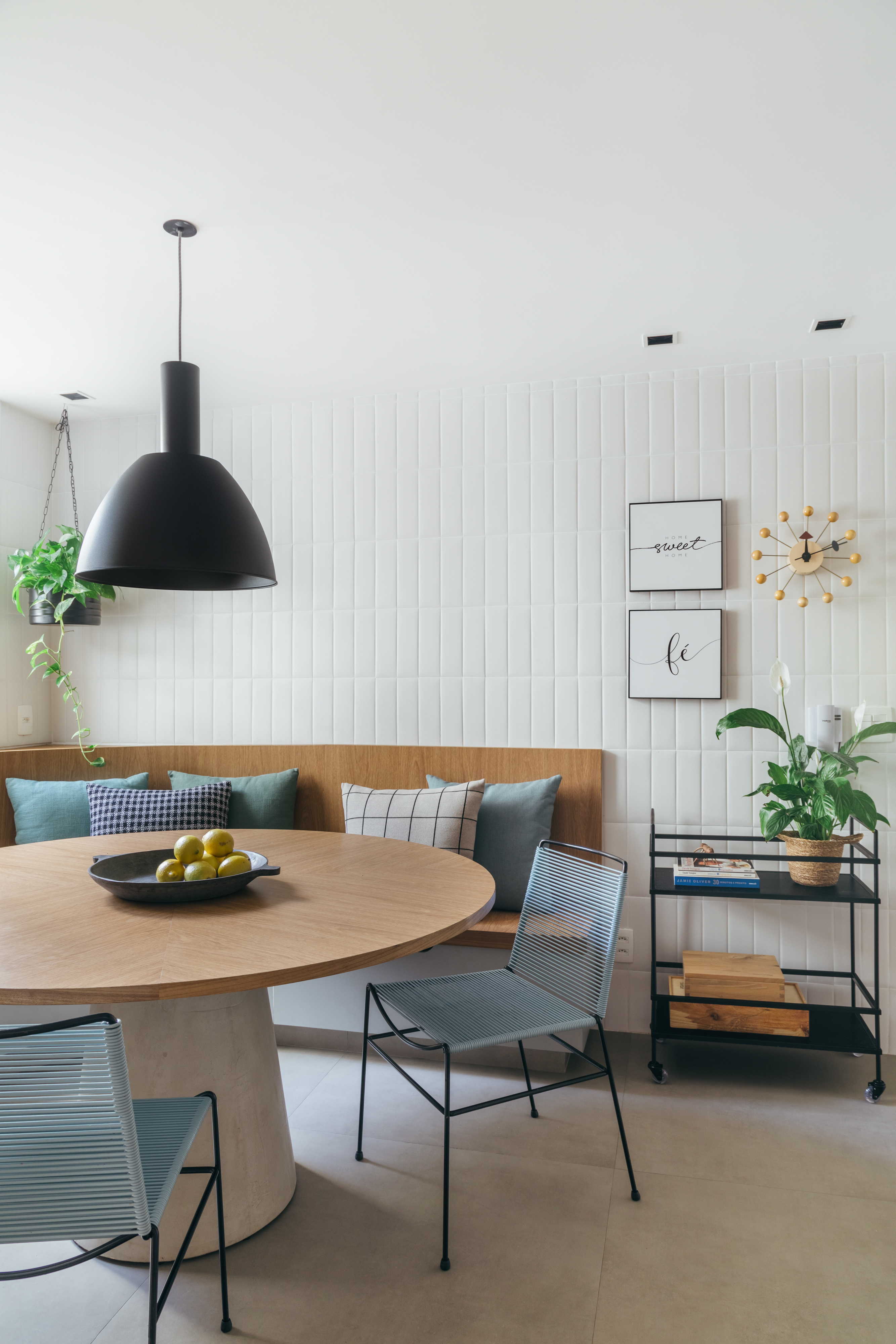 Projeto de Studio A+G Arquitetura. Na foto, cozinha clara com parede de azulejos, canto alemão e mesa redonda.