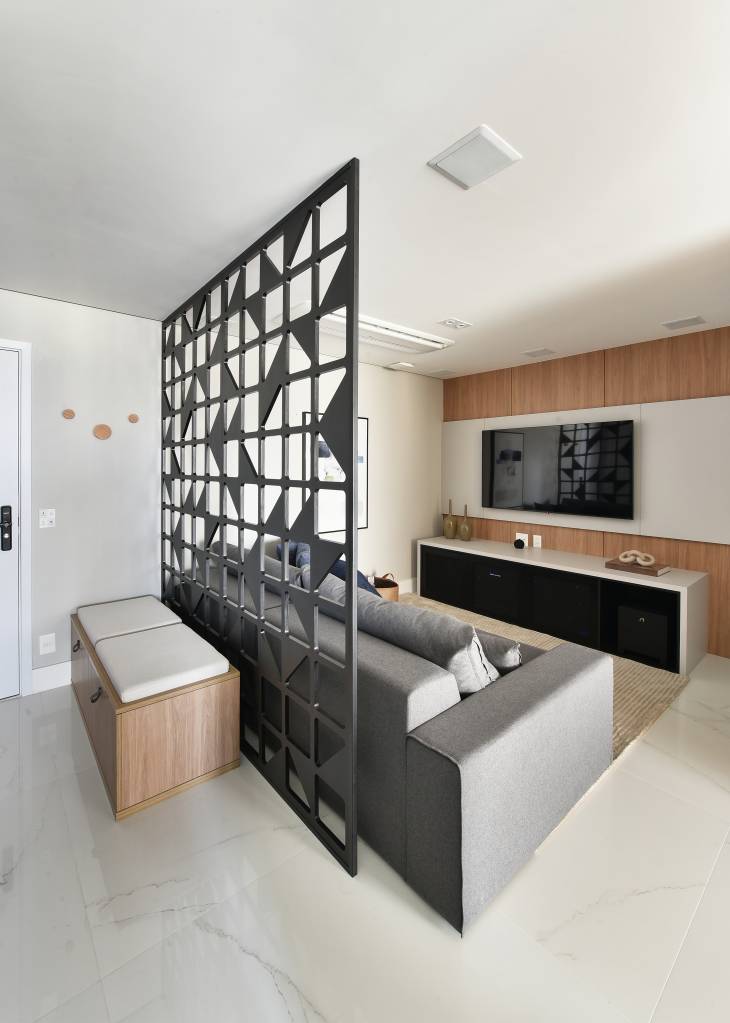 Projeto de Rosângela Pena. Na foto, sala de estar e sala de tv com divisória vazada atrás de sofá.