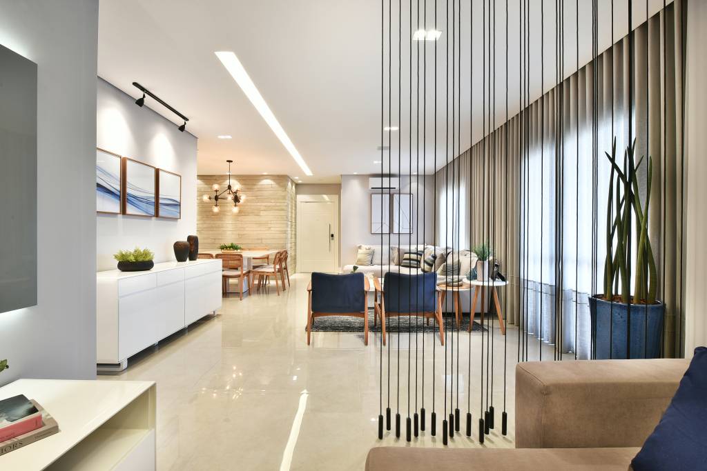 Projeto de Rosângela Pena. Na foto, sala de estar com piso de porcelanato e cortina de cordas como divisória.