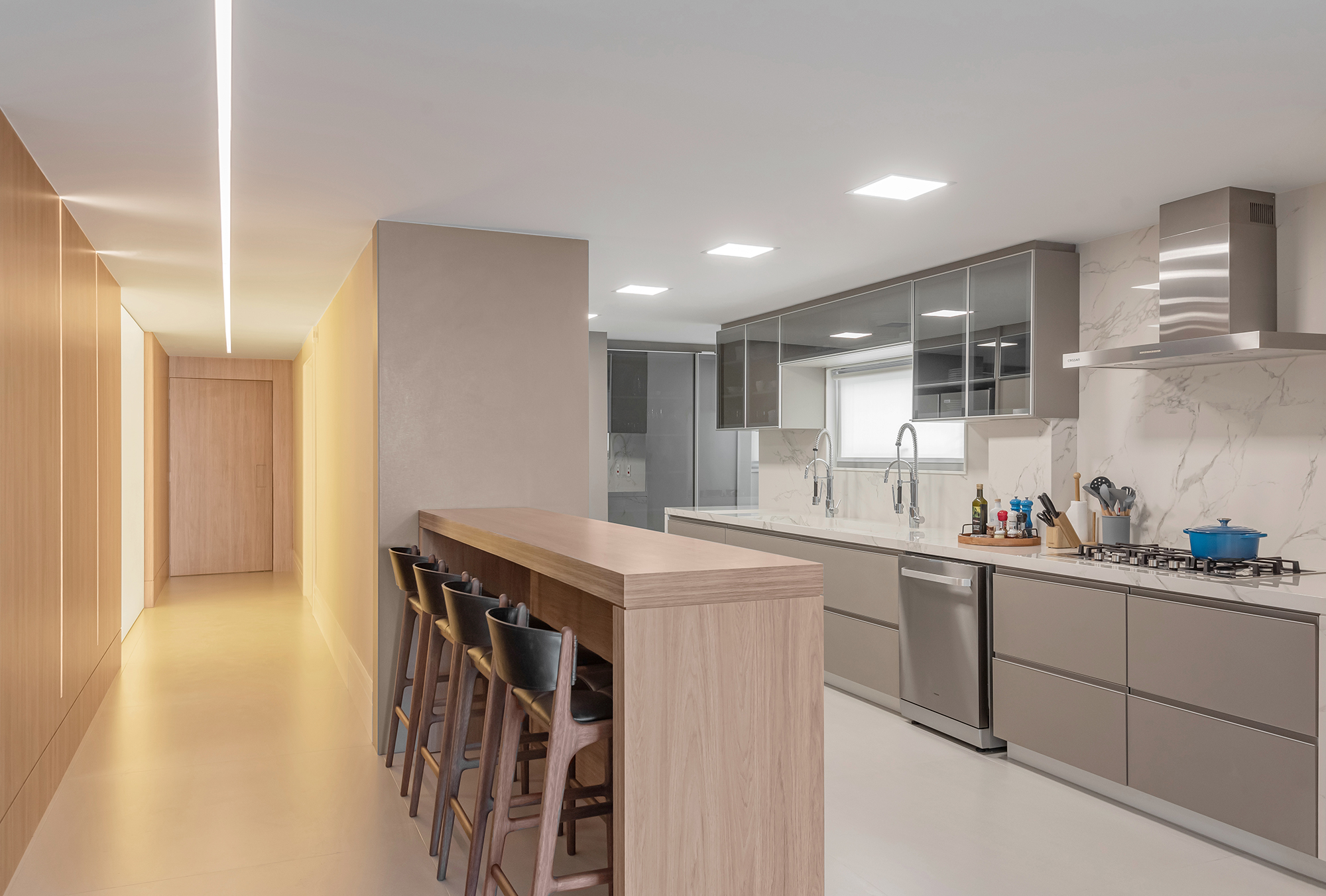 Dois apartamentos unidos criam casa de praia para a família em 370 m². Projeto de Maria Augusta Bittencourt, Na foto, cozinha com tampo de dekton. e bancada de refeições.