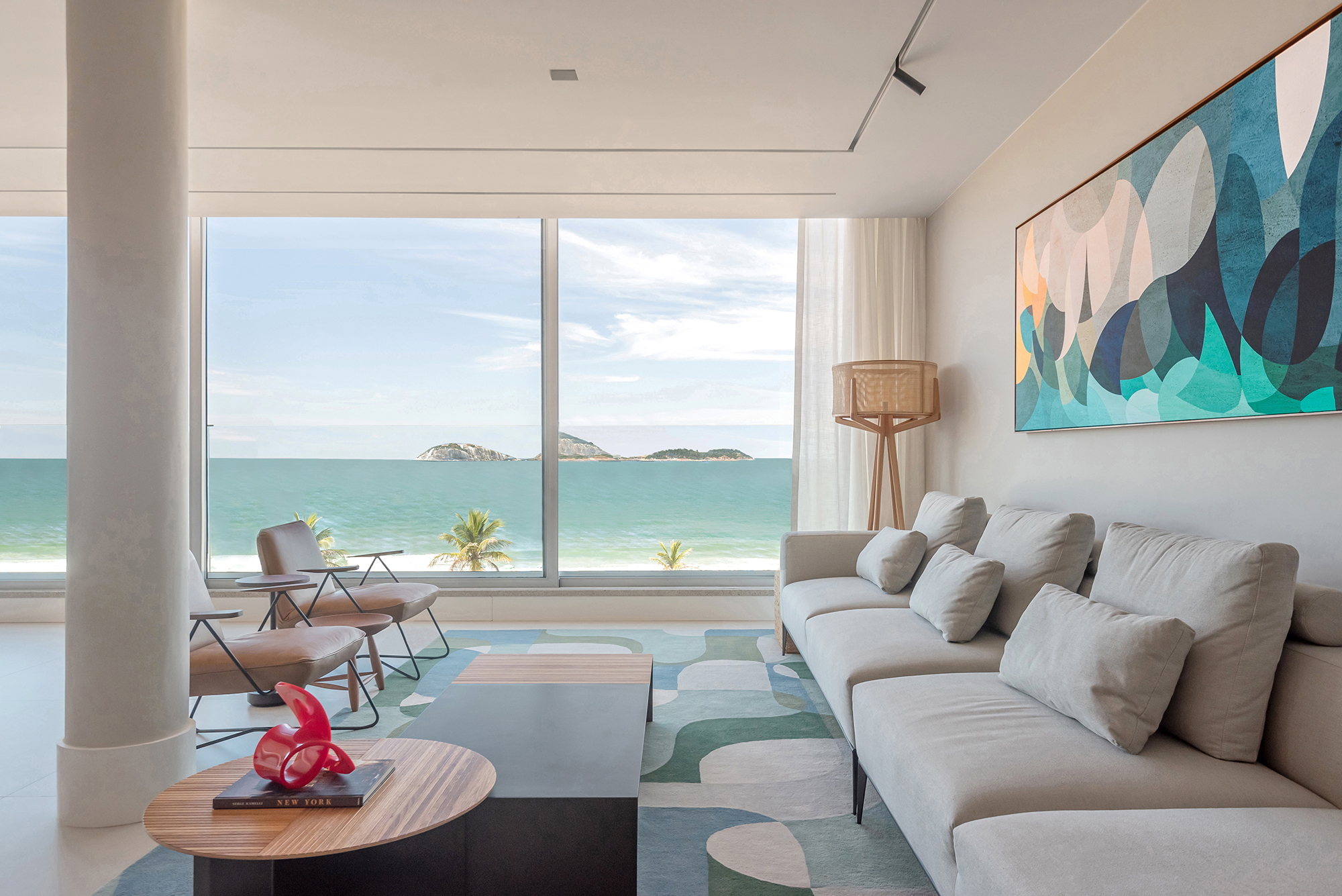 Dois apartamentos unidos criam casa de praia para a família em 370 m². Projeto de Maria Augusta Bittencourt, Na foto, sala de estar com tapete geométrico e vista para o mar.