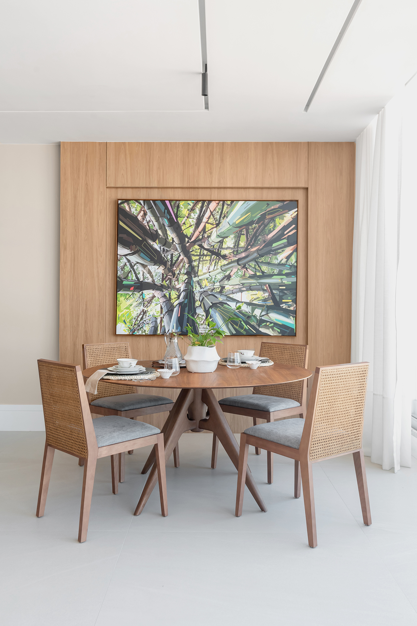 Dois apartamentos unidos criam casa de praia para a família em 370 m². Projeto de Maria Augusta Bittencourt. Na foto, sala de almoço com mesa redonda e quadro.