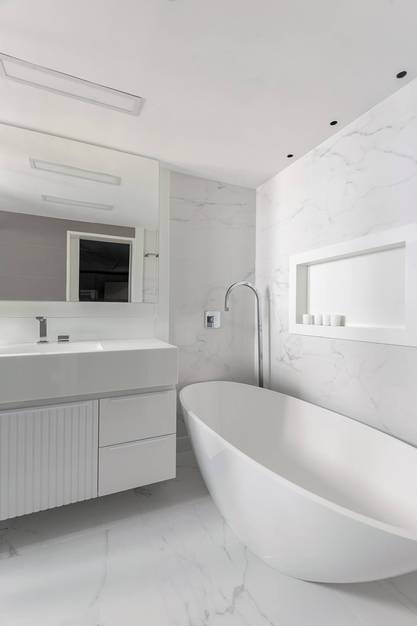 Dois apartamentos unidos criam casa de praia para a família em 370 m². Projeto de Maria Augusta Bittencourt, Na foto, banheiro com banheira e revestimentos brancos.