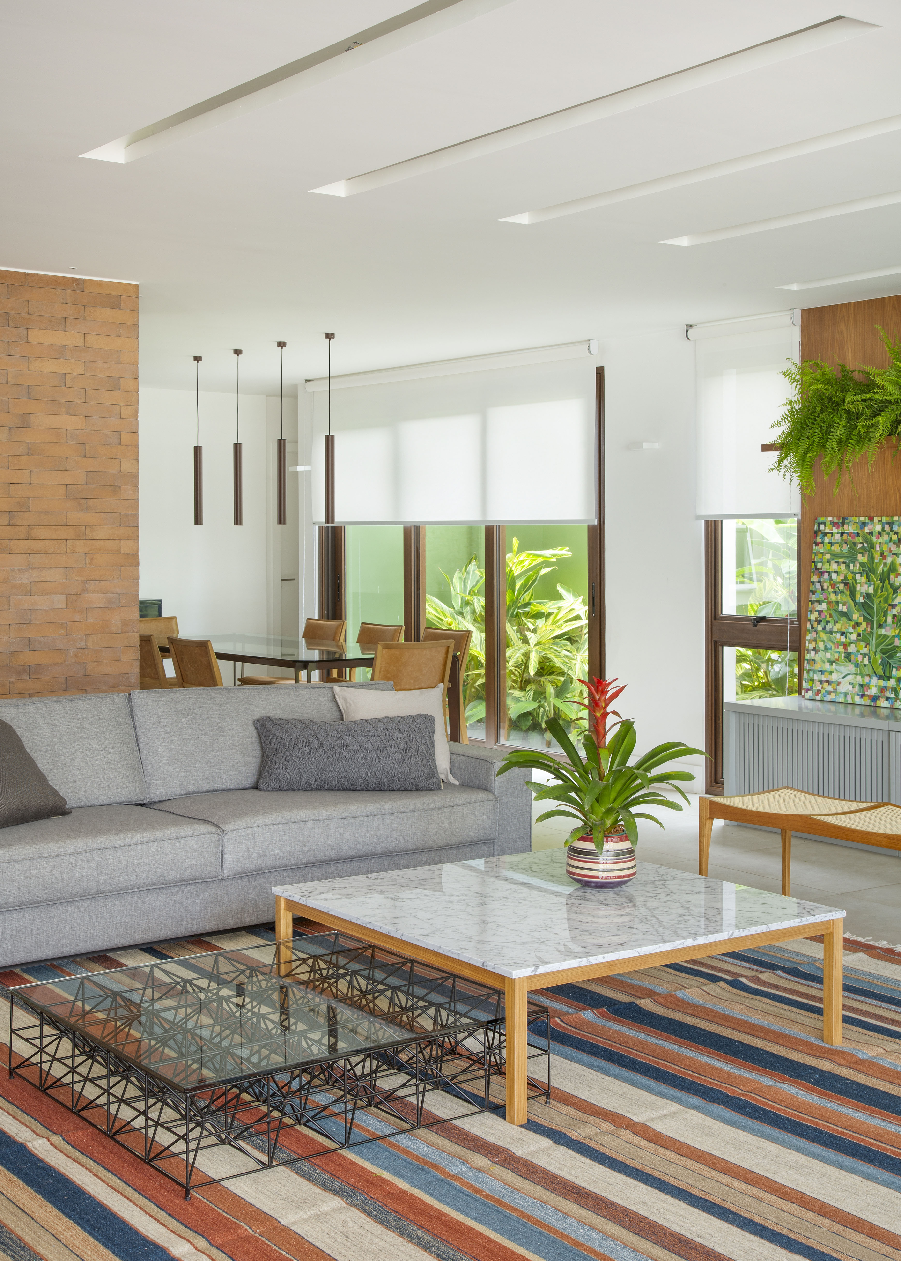 Projeto de Studio Duas Arquitetura. Na foto, sala de estar com tapete listrado colorido, sofá cinza e mesa de centro com tampo branco.