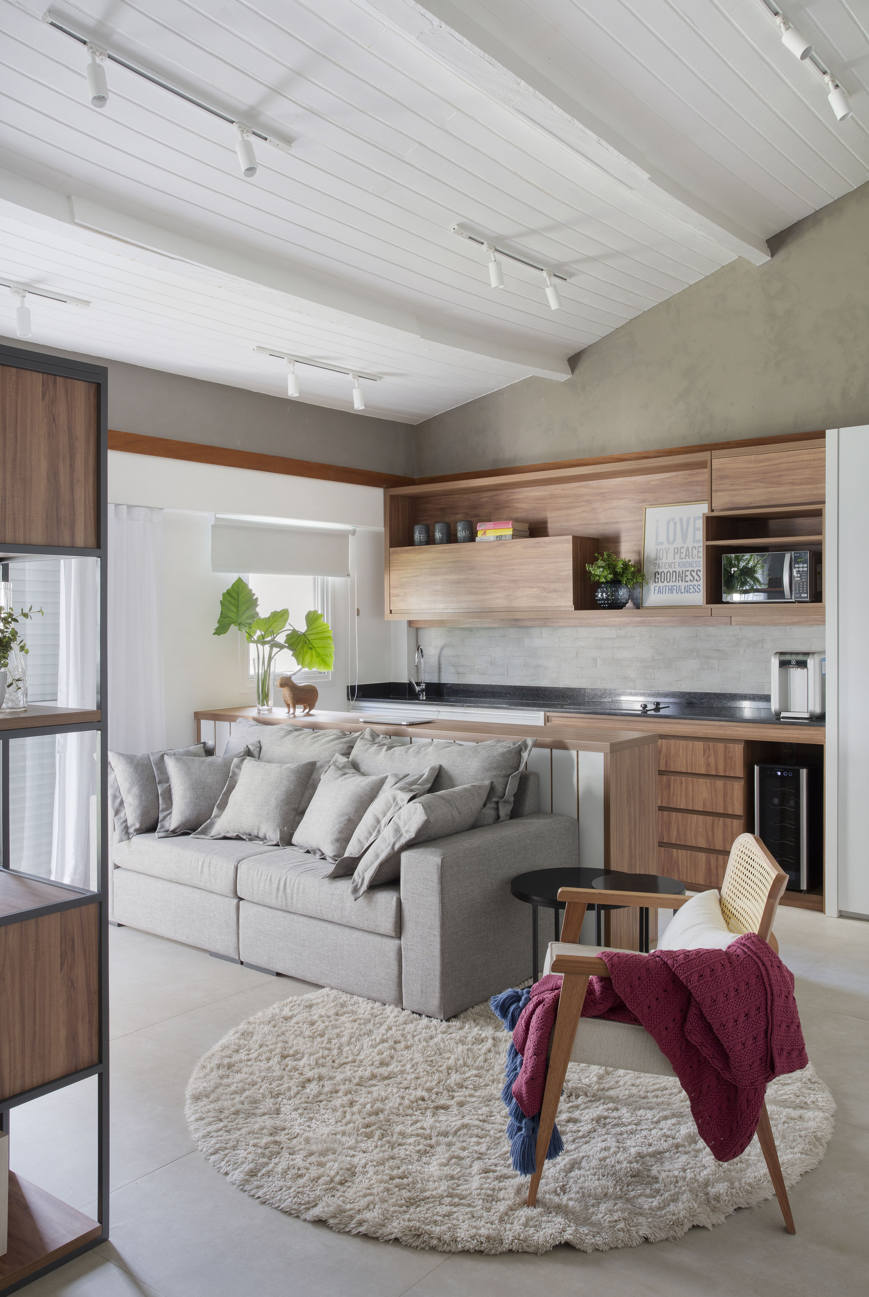 Projeto de Studio Duas Arquitetura. Na foto, loft com sofá cinza e cozinha integrada.