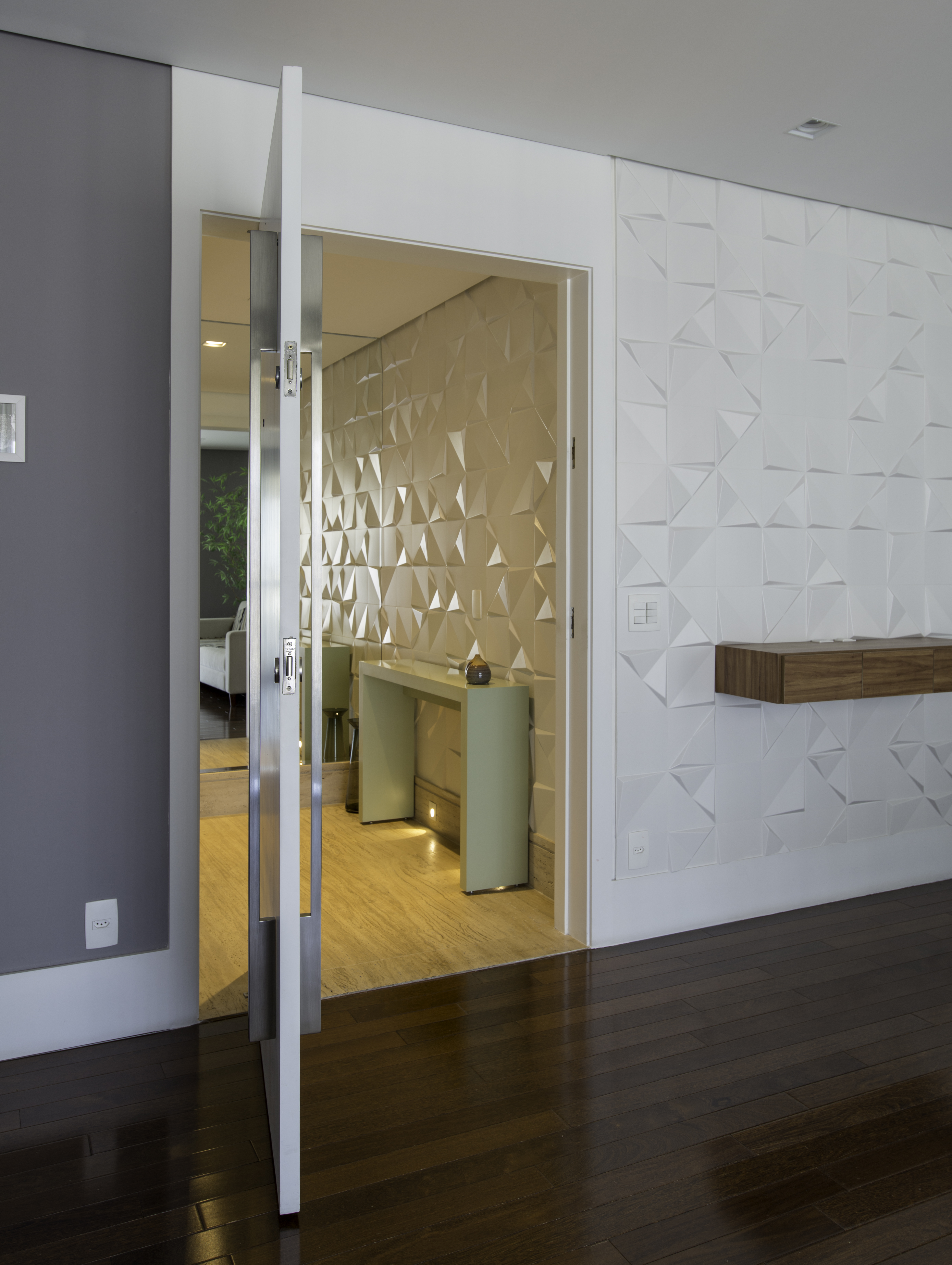 Projeto de Raízes Arquitetos. Na foto, hall de entrada com revestimento 3d e porta pivotante.