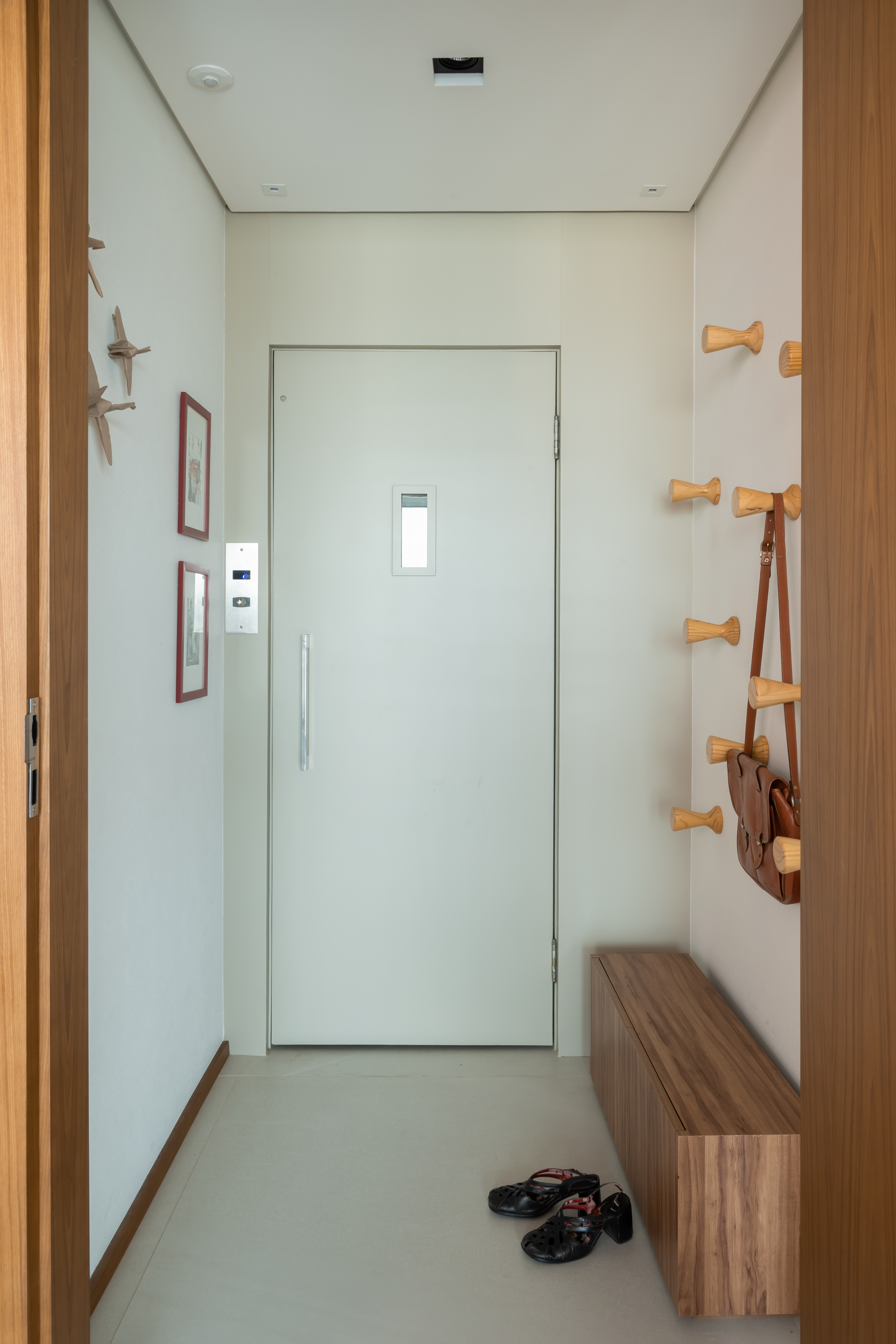 Projeto de Raízes Arquitetos. Na foto, hall de entrada com ganchos e cabideiros.