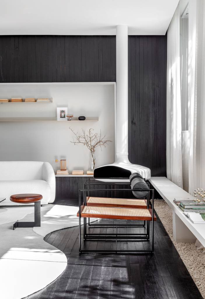 madeira-ebanizada-protagonista-sala-decor-branco-preto-barbara-ramos-credito-fabio-severo-(2) Madeira ebanizada é protagonista desta sala com décor branco e preto. Projeto de Barbara Ramos para a CASACOR Santa Catarina 2023. Na foto, sala de estar com lareira, sofá branco e pedras.
