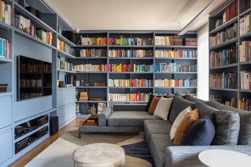 Projeto de Stal Arquitetura. Na foto, sala de estar com biblioteca. Estante de marcenaria em tom azul.