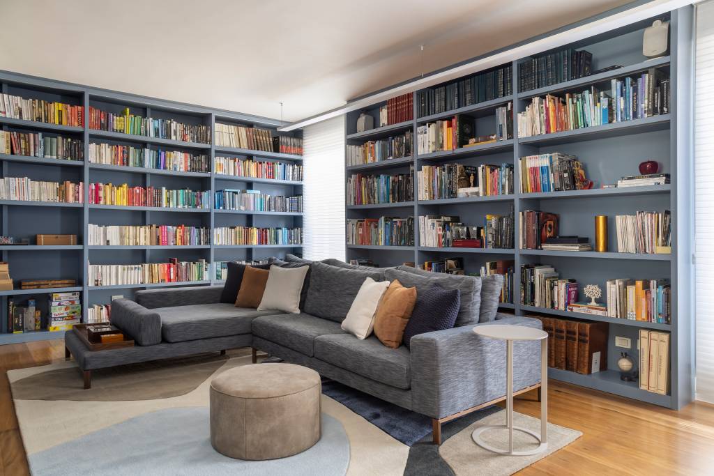 Projeto de Stal Arquitetura. Na foto, sala de estar com biblioteca. Estante de marcenaria em tom azul.