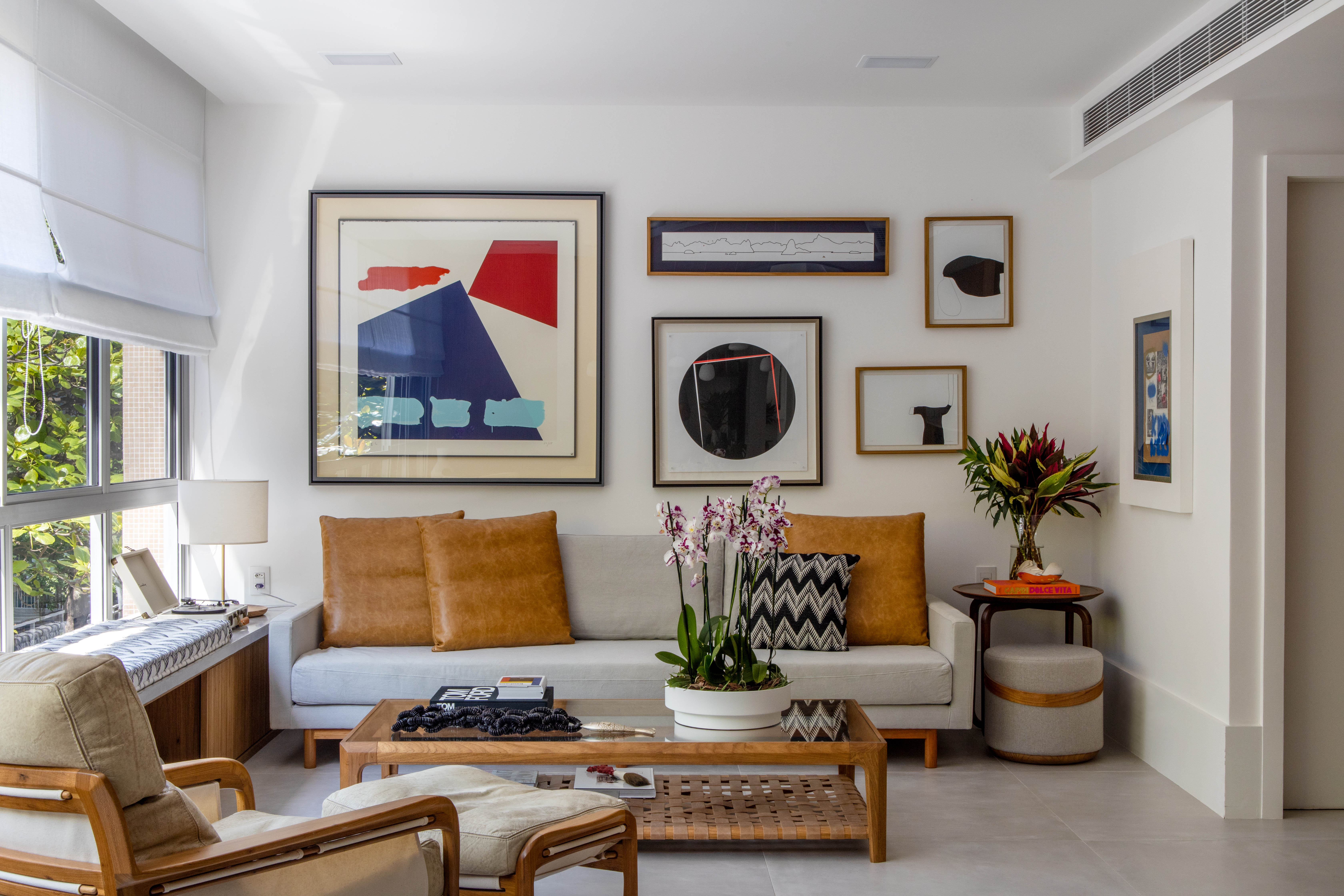 Painéis escondem e revelam ambientes neste apartamento de 130 m². Projeto de Mauricio Nóbrega. Na foto, sala com gallery wall e sofá branco.