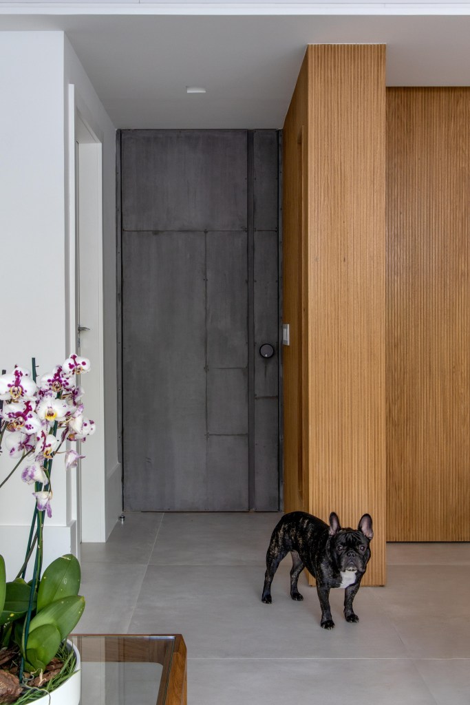 Painéis escondem e revelam ambientes neste apartamento de 130 m². Projeto de Mauricio Nóbrega. Na foto, porta de entrada com madeira pintada e painel ripado.