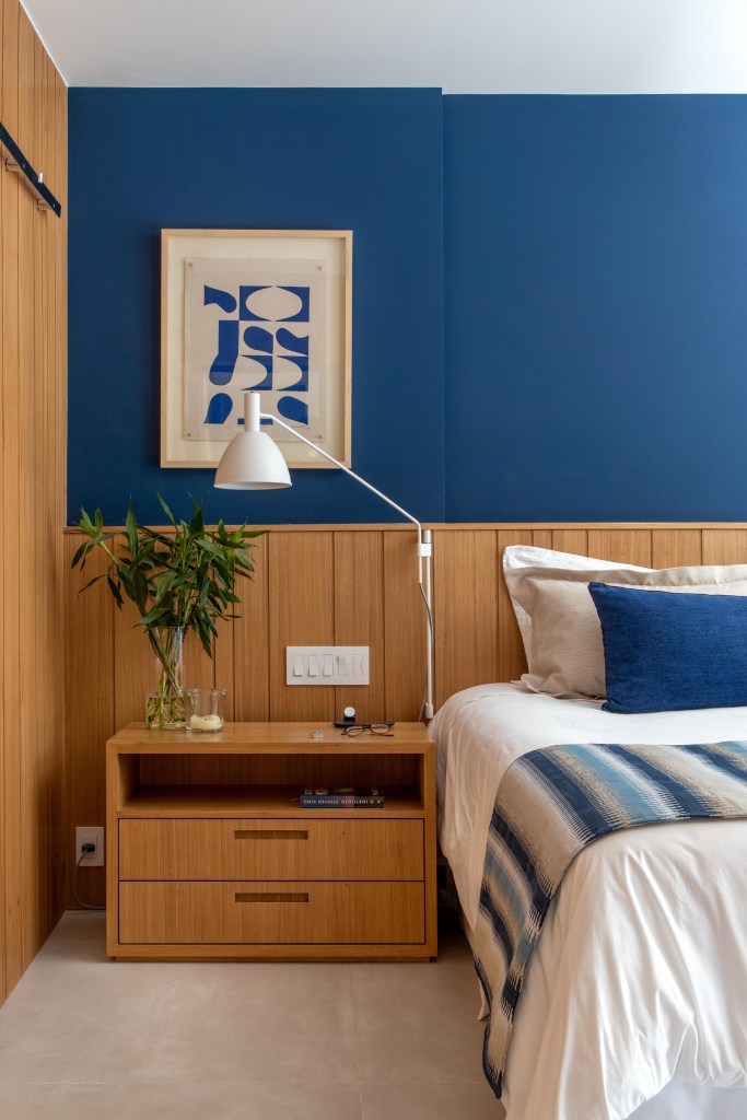 Painéis escondem e revelam ambientes neste apartamento de 130 m². Projeto de Mauricio Nóbrega. Na foto, quarto de casal com parede azul.
