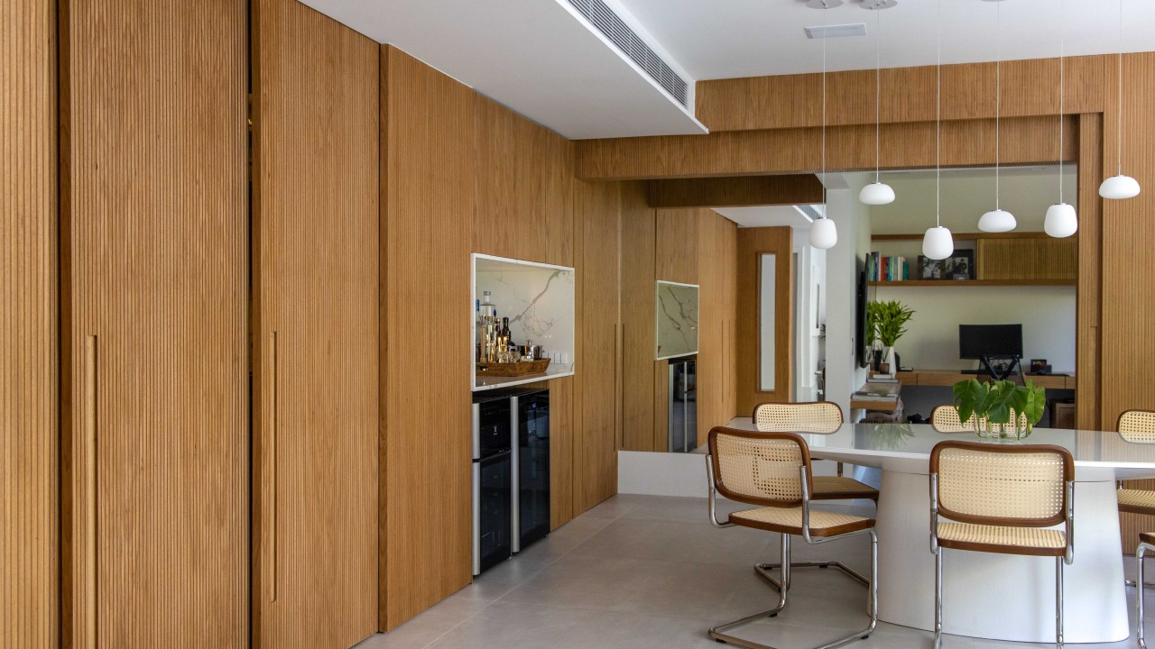 Painéis escondem e revelam ambientes neste apartamento de 130 m². Projeto de Mauricio Nóbrega. Na foto, cozinha com escritório integrado, Bar no nicho e portas de correr.