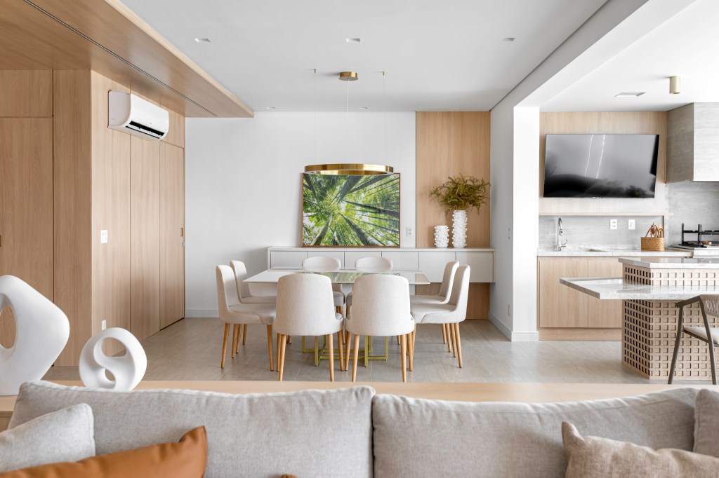 Projeto de NOP Arquitetura. Na foto, sala integrada com varanda gourmet e mesa de jantar branca e cadeiras brancas.