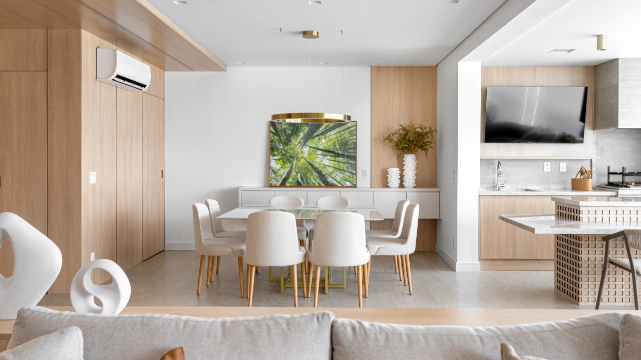 Projeto de NOP Arquitetura. Na foto, sala integrada com varanda gourmet e mesa de jantar branca e cadeiras brancas.