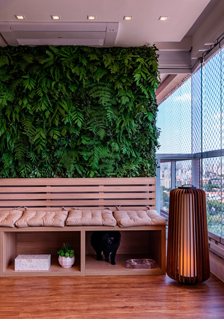 Pequenos plafons no teto e uma luminária de piso charmosa contribuem com a iluminação da varanda, que ganhou uma linda parede verde. Projeto da designer Eliana Franco.