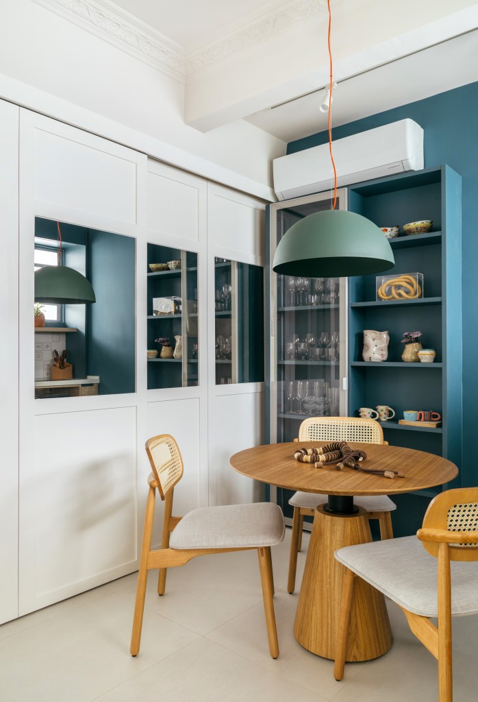 Projeto de Casa Cururu. Na foto, cozinha pequena com armário azul e mesa de madeira redonda com duas cadeiras.