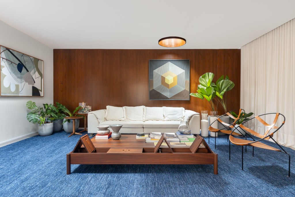 Salas de 60 m² celebram momentos em família e design brasileiro. Projeto de Maria Araujo para a CASACOR Brasilia 2023. Na foto, sala de estar com tapete azul e parede de madeira.